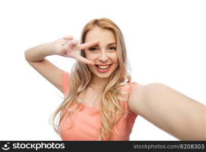 emotions, expressions and people concept - happy smiling young woman taking selfie and showing peace hand sign