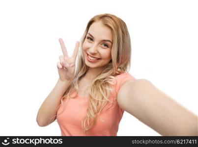emotions, expressions and people concept - happy smiling young woman taking selfie and showing peace hand sign