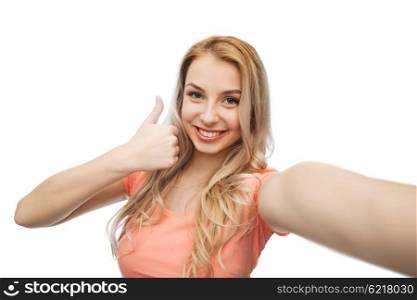 emotions, expressions and people concept - happy smiling young woman taking selfie and showing thumbs up