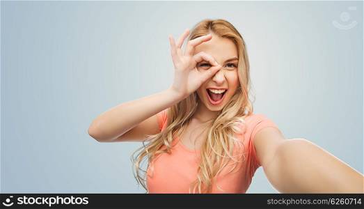 emotions, expressions and people concept - happy smiling young woman taking selfie over gray background