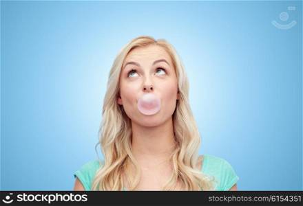 emotions, expressions and people concept - happy young woman or teenage girl chewing gum over blue background