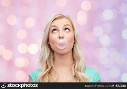 emotions, expressions and people concept - happy young woman or teenage girl chewing gum over pink holidays lights background