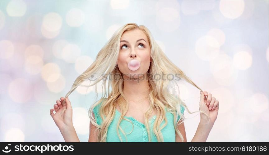 emotions, expressions and people concept - happy young woman or teenage girl chewing gum over holidays lights background