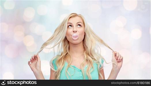 emotions, expressions and people concept - happy young woman or teenage girl chewing gum over holidays lights background