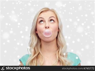 emotions, expressions and people concept - happy young woman or teenage girl chewing gum over snow
