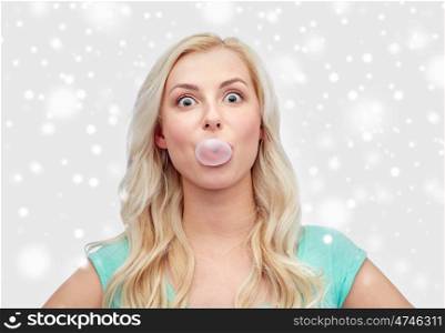 emotions, expressions and people concept - happy young woman or teenage girl chewing gum over snow