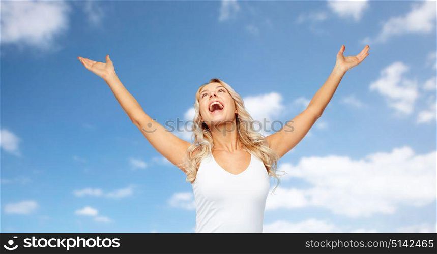 emotions, expressions and people concept - happy young woman with raised hands celebrating victory over blue sky and clouds background. happy woman celebrating victory over blue sky