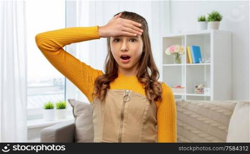 emotions, expressions and people concept - shocked or forgetful young teenage girl holding to her head over home background. shocked teenage girl holding to her head at home