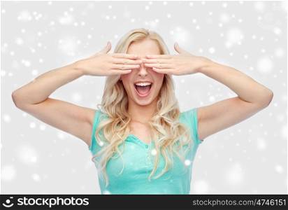 emotions, expressions and people concept - smiling young woman or teenage girl covering her eyes with palms over snow