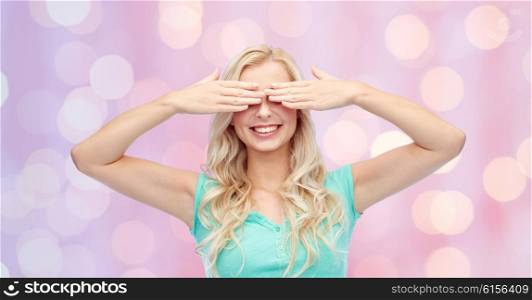 emotions, expressions and people concept - smiling young woman or teenage girl covering her eyes with palms over pink holidays lights background