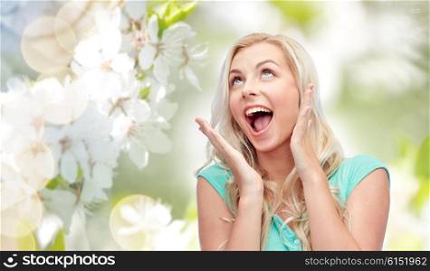 emotions, expressions and people concept - surprised smiling young woman or teenage girl over natural spring background
