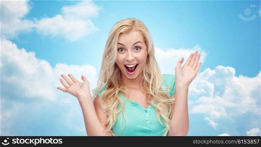 emotions, expressions and people concept - surprised smiling young woman or teenage girl over over blue sky and clouds background
