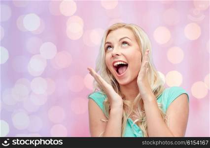 emotions, expressions and people concept - surprised smiling young woman or teenage girl over pink holidays lights background