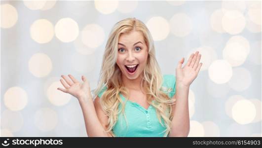 emotions, expressions and people concept - surprised smiling young woman or teenage girl over holidays lights background