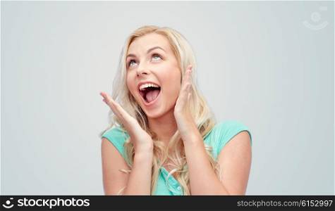 emotions, expressions and people concept - surprised smiling young woman or teenage girl over gray background