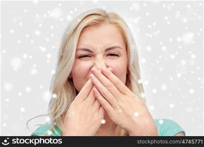 emotions, expressions, embarrassment, and people concept - young woman or teenage girl wrinkling and closing her nose of unpleasant smell over snow