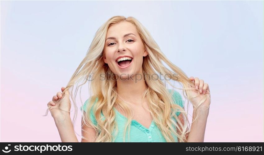 emotions, expressions, hairstyle and people concept - smiling young woman or teenage girl holding her strand of hair over rose quartz and serenity gradient background