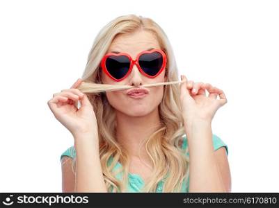 emotions, expressions, hairstyle and people concept - smiling young woman or teenage girl making mustache with strand of hair