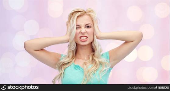 emotions, expressions, stress and people concept - young woman holding to her head and screaming over pink holidays lights background