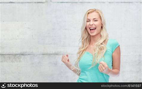 emotions, expressions, success and people concept - happy young woman or teenage girl celebrating victory over gray concrete wall background