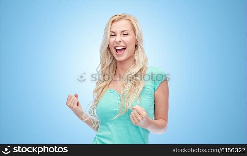 emotions, expressions, success and people concept - happy young woman or teenage girl celebrating victory over blue background
