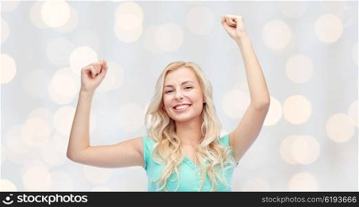 emotions, expressions, success and people concept - happy young woman or teenage girl celebrating victory over holidays lights background