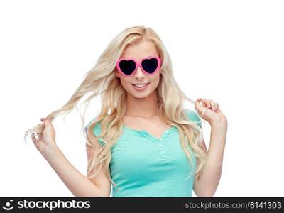 emotions, expressions, summer and people concept - smiling young woman or teenage girl in heart shape sunglasses holding her strand of hair