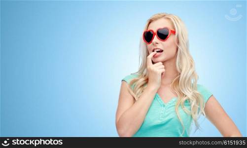 emotions, expressions, summer and people concept - smiling young woman or teenage girl in sunglasses over blue background