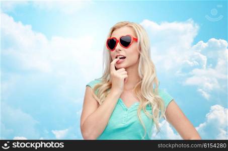 emotions, expressions, summer and people concept - smiling young woman or teenage girl in sunglasses over blue sky and clouds background