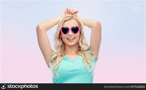 emotions, expressions, summer and people concept - smiling young woman or teenage girl in heart shape sunglasses over rose quartz and serenity gradient background