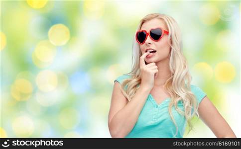 emotions, expressions, summer and people concept - smiling young woman or teenage girl in sunglasses over summer green lights background