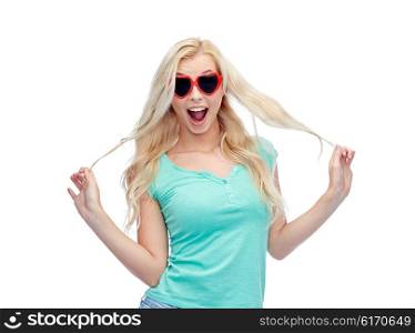 emotions, expressions, summer and people concept - smiling young woman or teenage girl in heart shape sunglasses holding her strand of hair