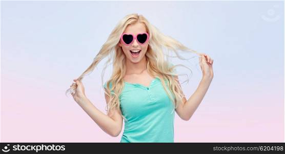 emotions, expressions, summer and people concept - smiling young woman or teenage girl in sunglasses holding her strand of hair over rose quartz and serenity gradient background