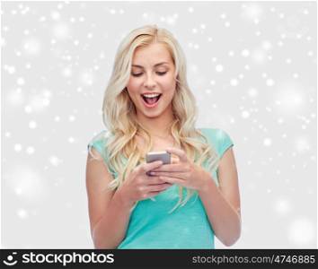 emotions, expressions, technology and people concept - smiling young woman or teenage girl texting on smartphone over snow