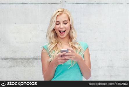 emotions, expressions, technology and people concept - smiling young woman or teenage girl texting on smartphone over gray concrete wall background