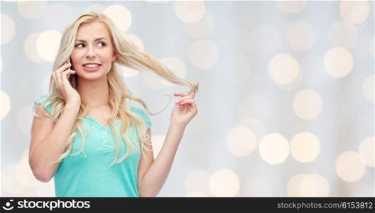 emotions, expressions, technology and people concept - smiling young woman or teenage girl calling on smartphone over holidays lights background