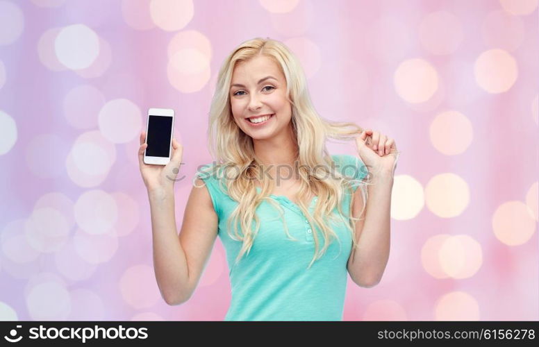 emotions, expressions, technology and people concept - smiling young woman or teenage girl showing blank smartphone screen over pink holidays lights background