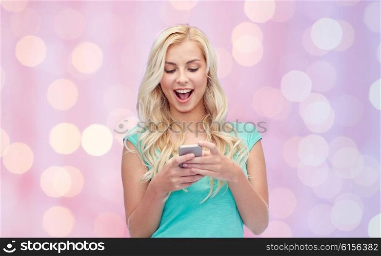 emotions, expressions, technology and people concept - smiling young woman or teenage girl texting on smartphone over pink holidays lights background