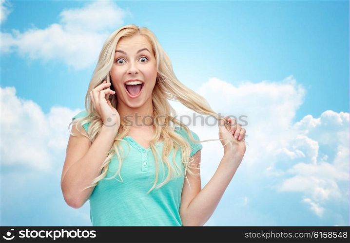 emotions, expressions, technology and people concept - smiling young woman or teenage girl calling on smartphone over blue sky and clouds background