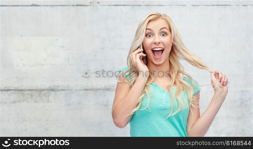 emotions, expressions, technology and people concept - smiling young woman or teenage girl calling on smartphone over gray concrete wall background
