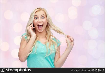 emotions, expressions, technology and people concept - smiling young woman or teenage girl calling on smartphone over pink holidays lights background