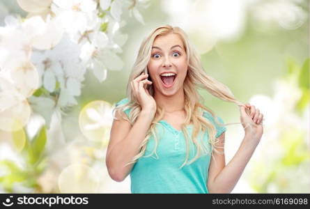 emotions, expressions, technology and people concept - smiling young woman or teenage girl calling on smartphone over natural spring cherry blossom background