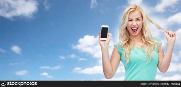 emotions, expressions, technology and people concept - smiling young woman or teenage girl showing blank smartphone screen and winking over blue sky and clouds background