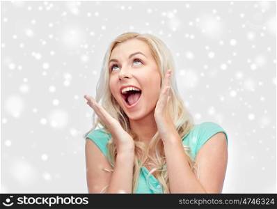 emotions, expressions, winter holidays, christmas and people concept - surprised smiling young woman or teenage girl over snow
