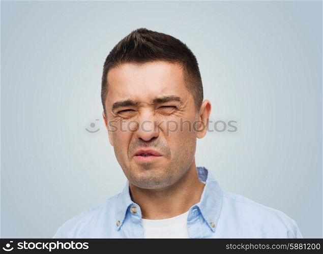 emotions, facial expression and people concept - man wrying of unpleasant smell over gray background