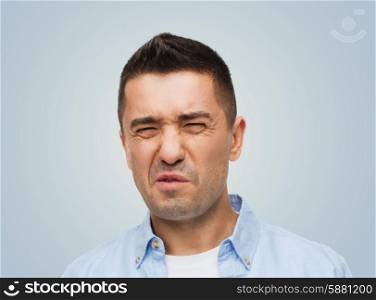 emotions, facial expression and people concept - man wrying of unpleasant smell over gray background