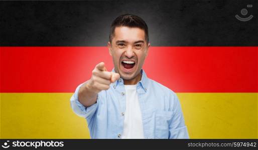 emotions, patriotism, citizenship, gesture and people concept - angry man shouting and pointing finger on you over german flag background