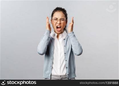 Emotions, people and lifestyle concept. Aggressive young annoyed asian woman have emotional working burnout, screaming with hate and rage, staring furious grimacing, shaking hands in anger.. Emotions, people and lifestyle concept. Aggressive young annoyed asian woman have emotional working burnout, screaming with hate and rage, staring furious grimacing, shaking hands in anger