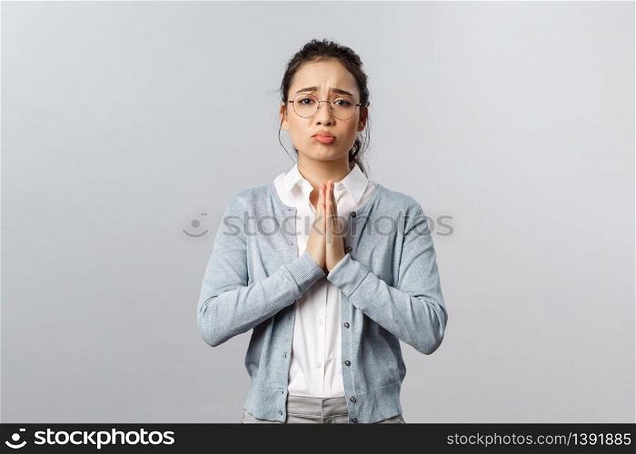 Emotions, people and lifestyle concept. Pretty please help me out. Portrait of cute, adorable asian woman asking coworker cover her, hold hands in pray, pleading for favour, standing grey background.. Emotions, people and lifestyle concept. Pretty please help me out. Portrait of cute, adorable asian woman asking coworker cover her, hold hands in pray, pleading for favour, standing grey background