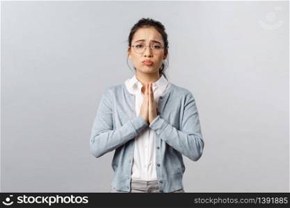 Emotions, people and lifestyle concept. Pretty please help me out. Portrait of cute, adorable asian woman asking coworker cover her, hold hands in pray, pleading for favour, standing grey background.. Emotions, people and lifestyle concept. Pretty please help me out. Portrait of cute, adorable asian woman asking coworker cover her, hold hands in pray, pleading for favour, standing grey background